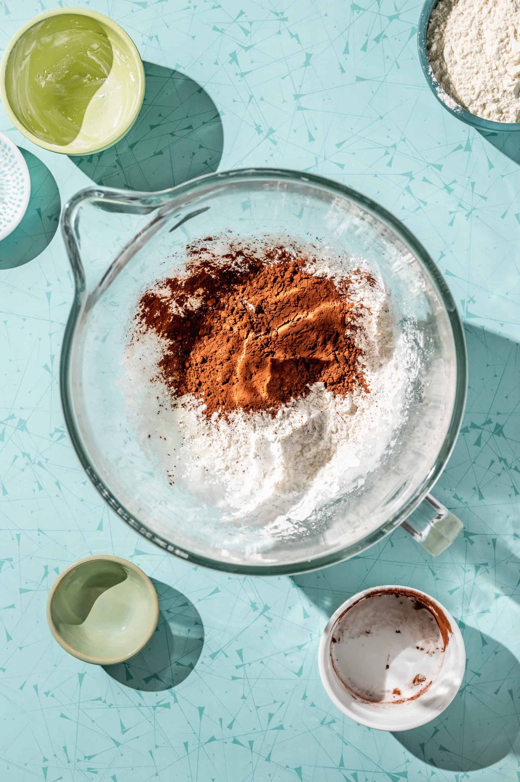 glass mixing bowl with cocoa powder and cornstarch on top of dough mixture before mixing