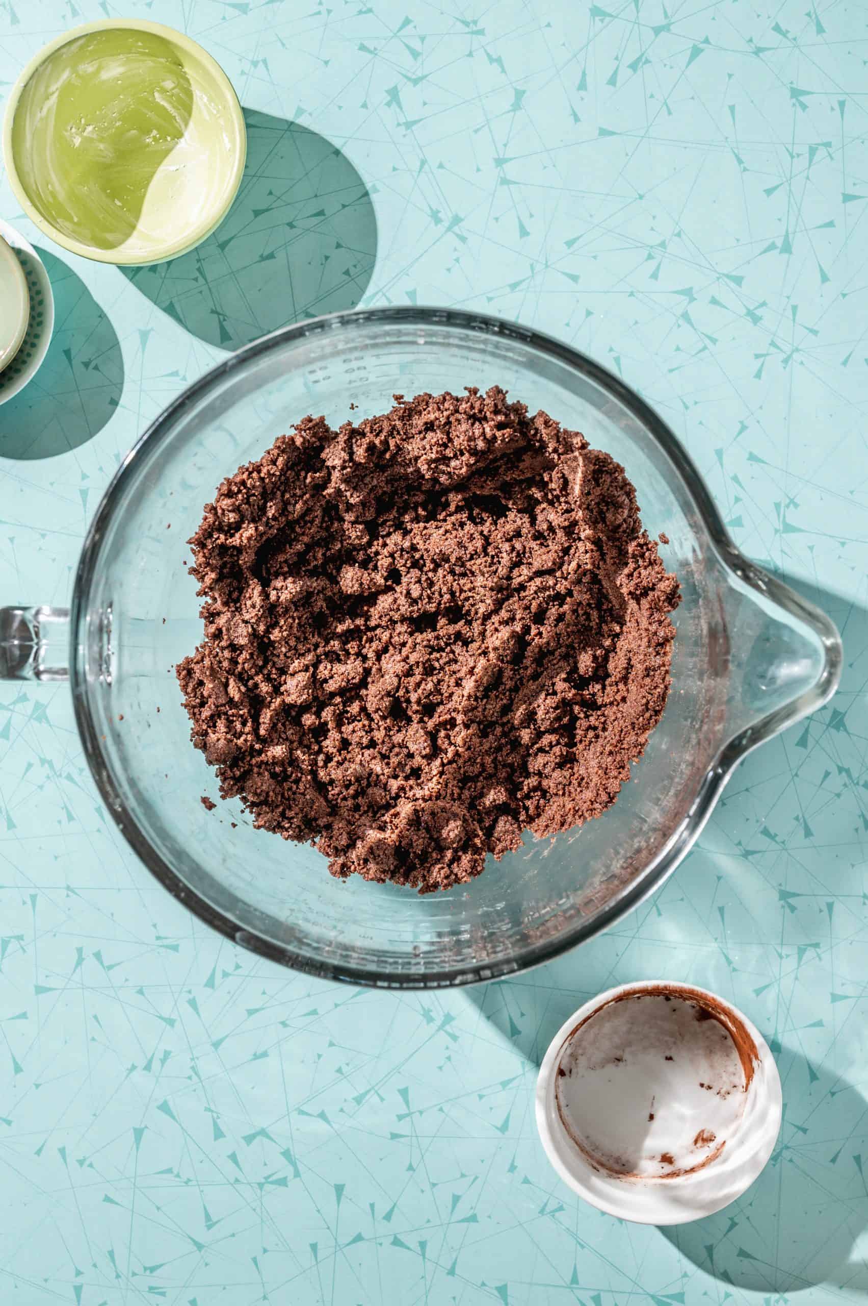 crumbly brown copycat thin mint cookie dough in a large glass mixing bowl