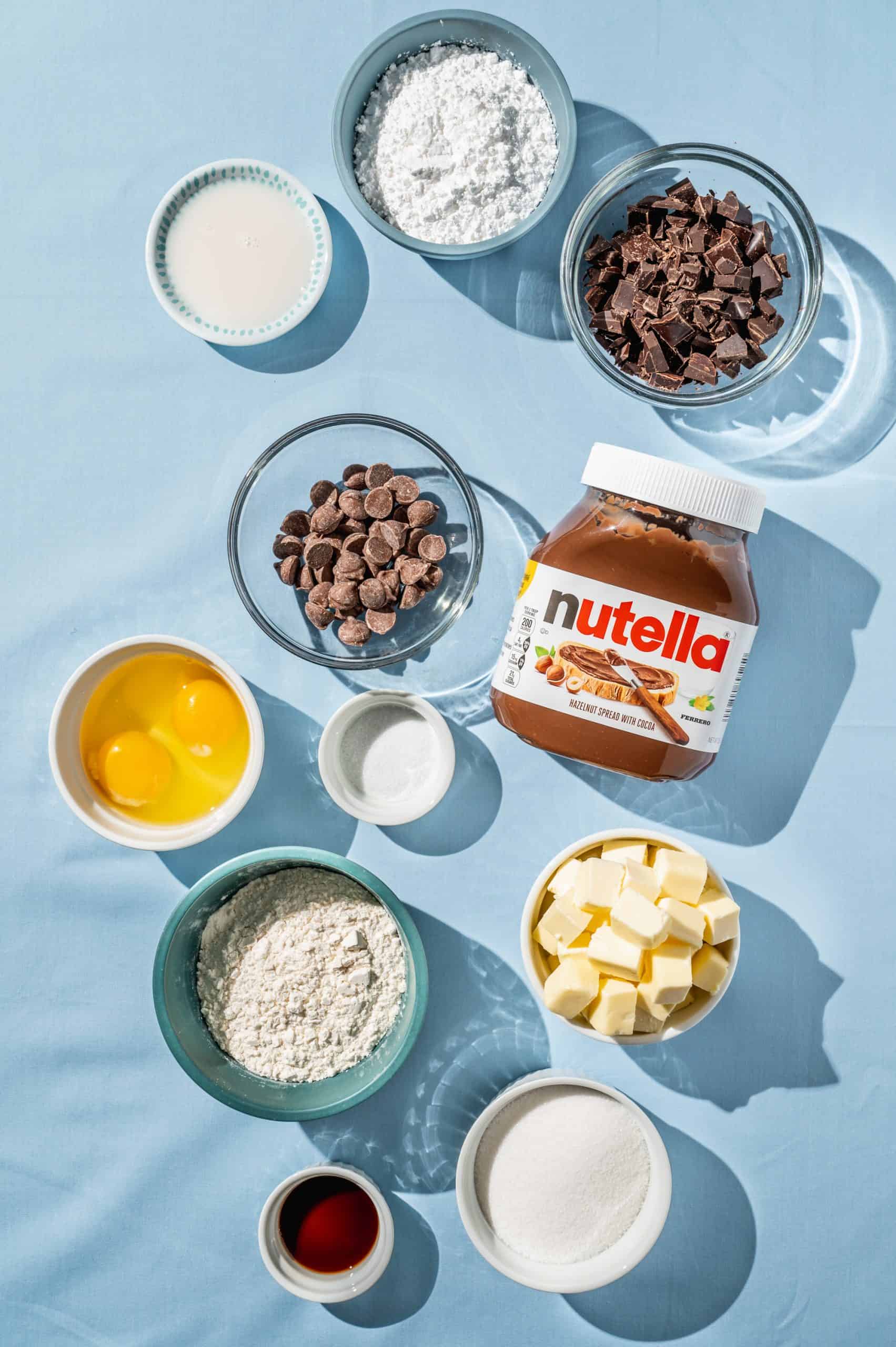 ingredients to make brownies with nutella frosting- chocolate, eggs, butter, flour, sugar, salt, vanilla, nutella