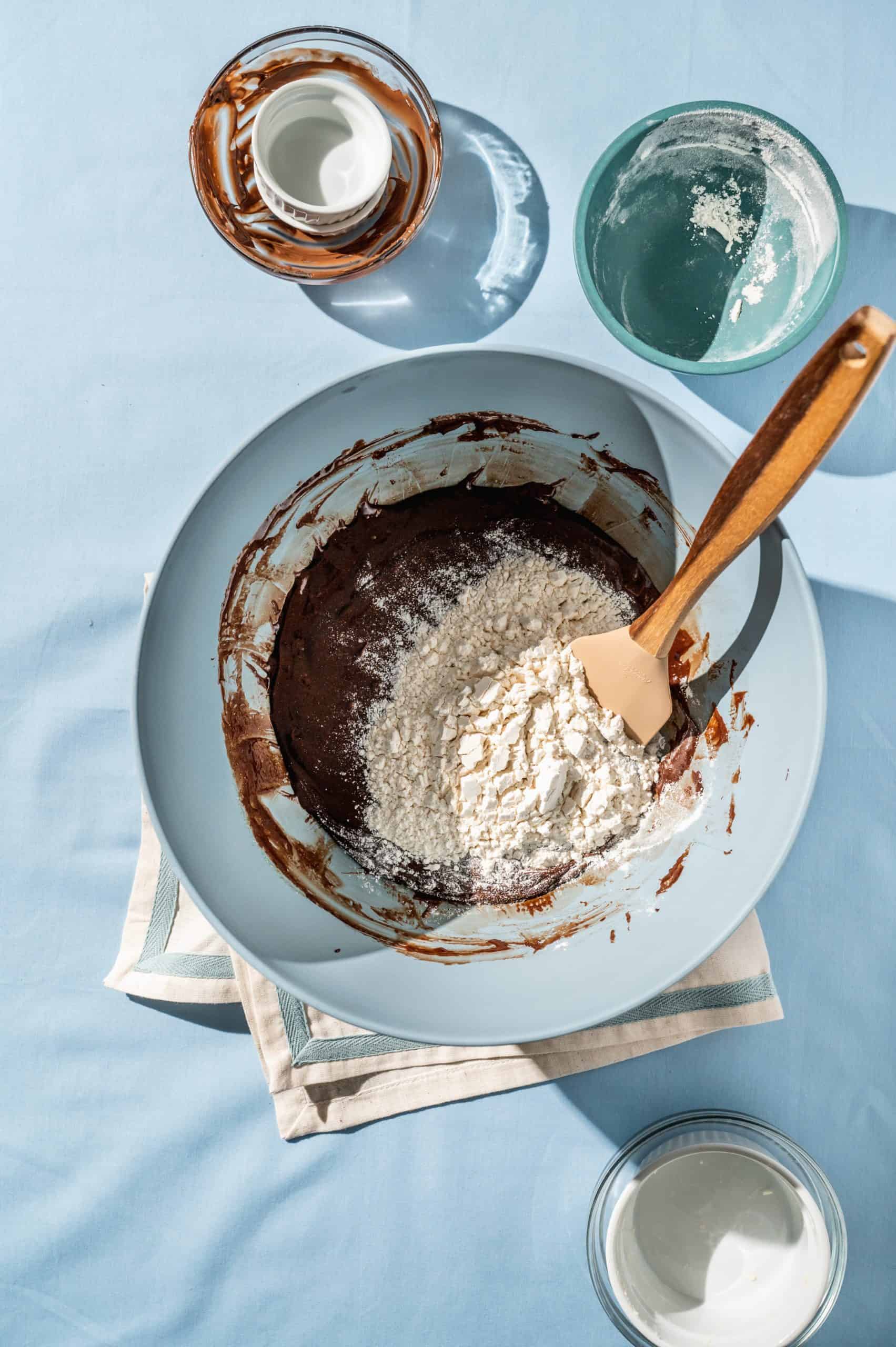 mixing bowl with chocolate batter mixture and flour on top before mixing