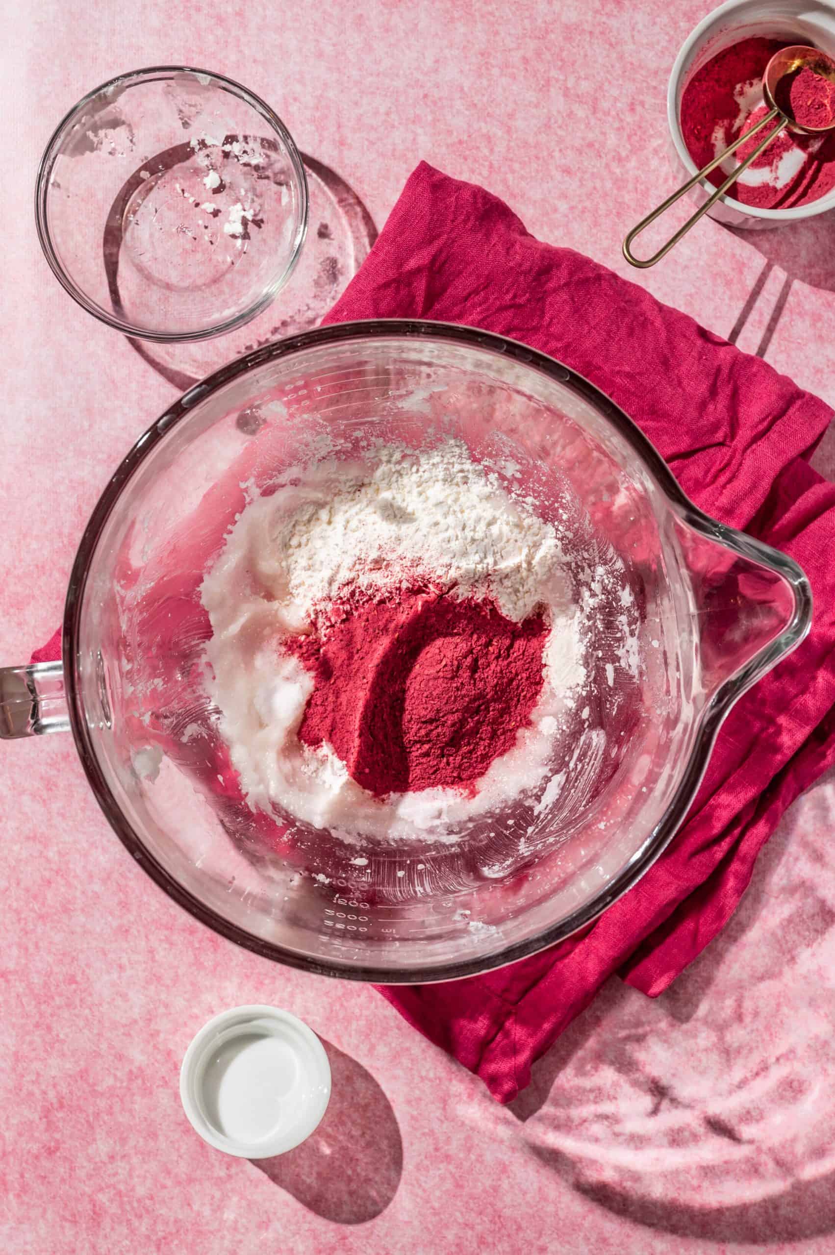 glass mixing bowl with cornstarch and raspberry powder on top of shortening and sugar before mixing