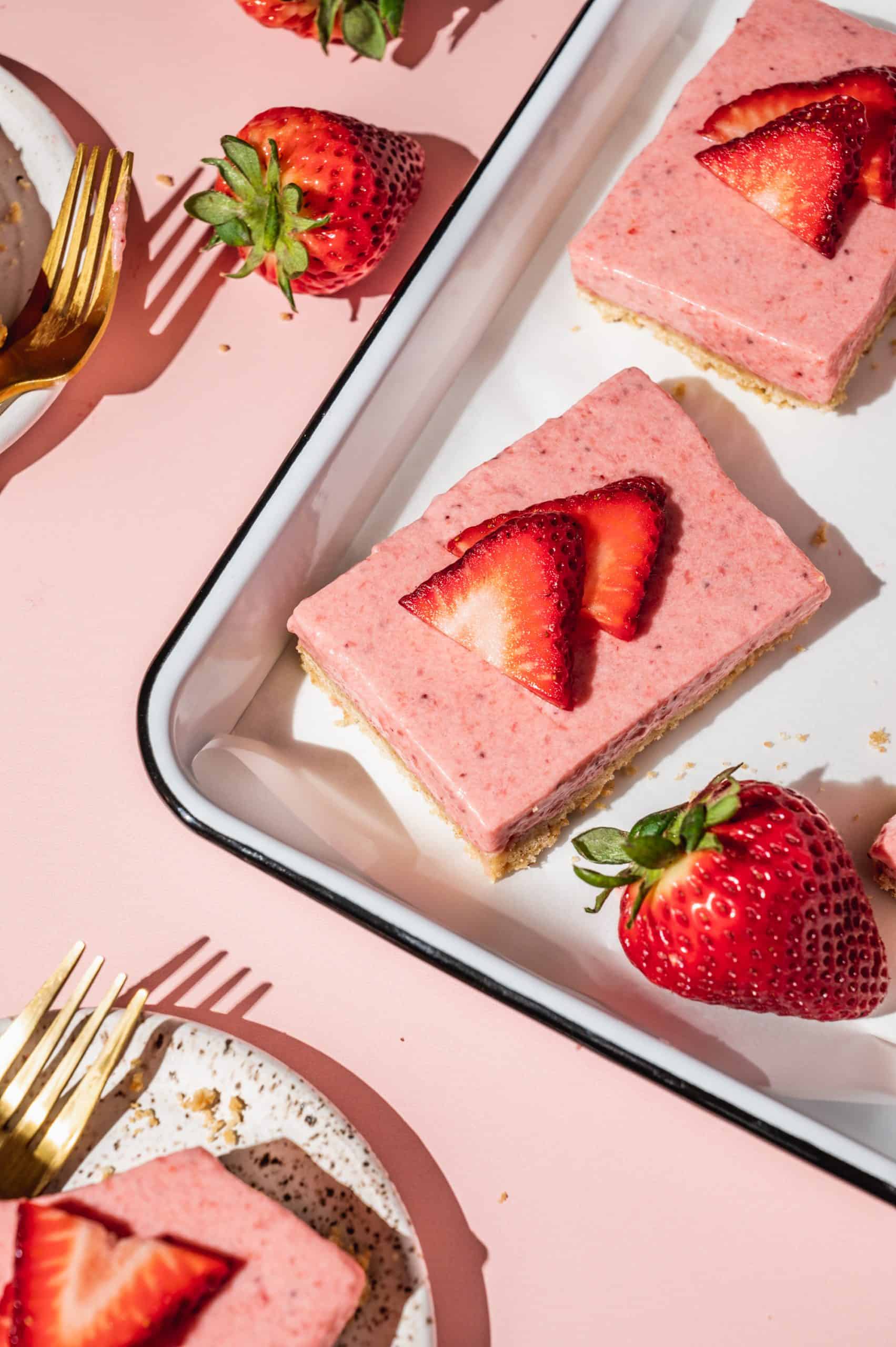 strawberry pie bars garnished with sliced strawberries on a white tray