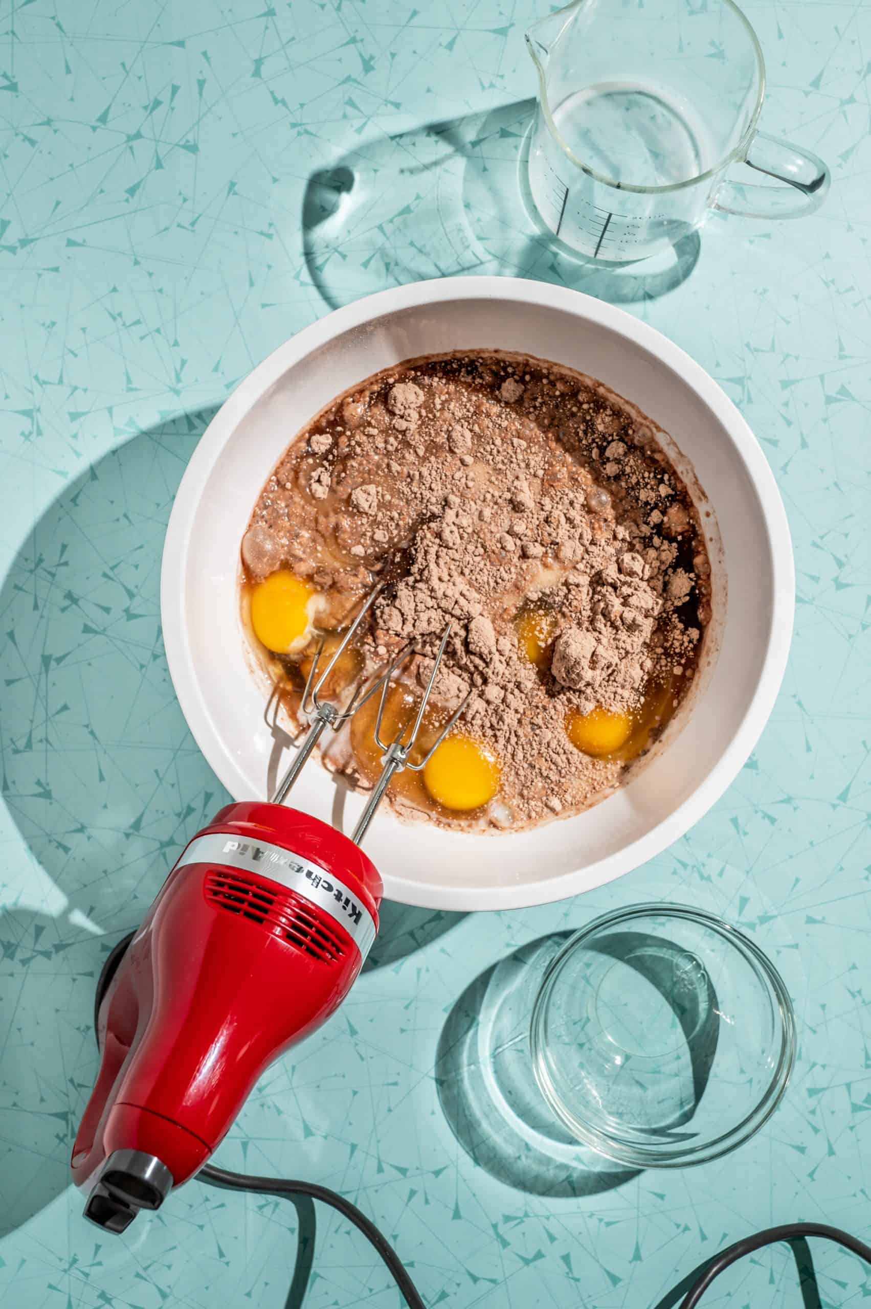 bowl with chocolate cake mix, eggs, milk, and oil, mixed with a handheld electric beater