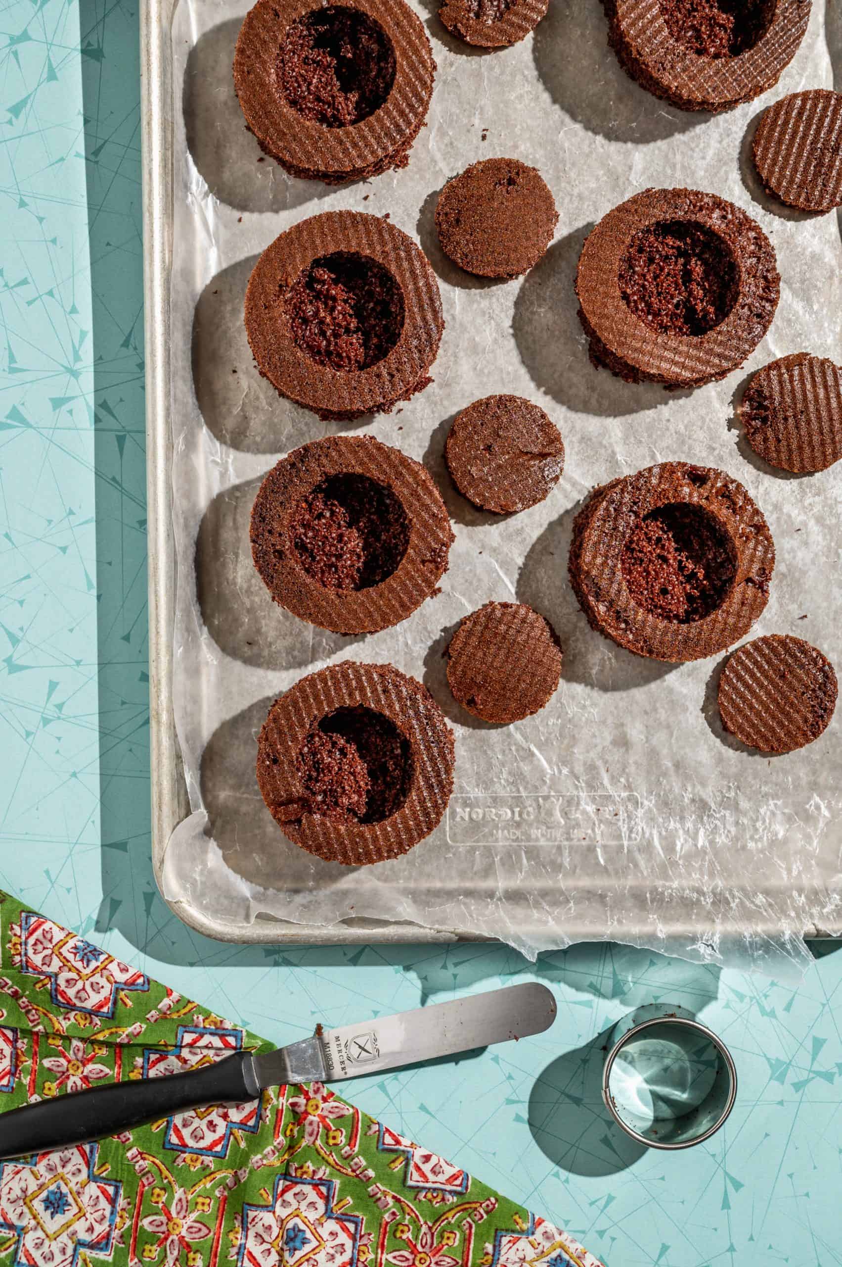 mini chocolate cakes lined up on a tray with centers removed to hollow out inside