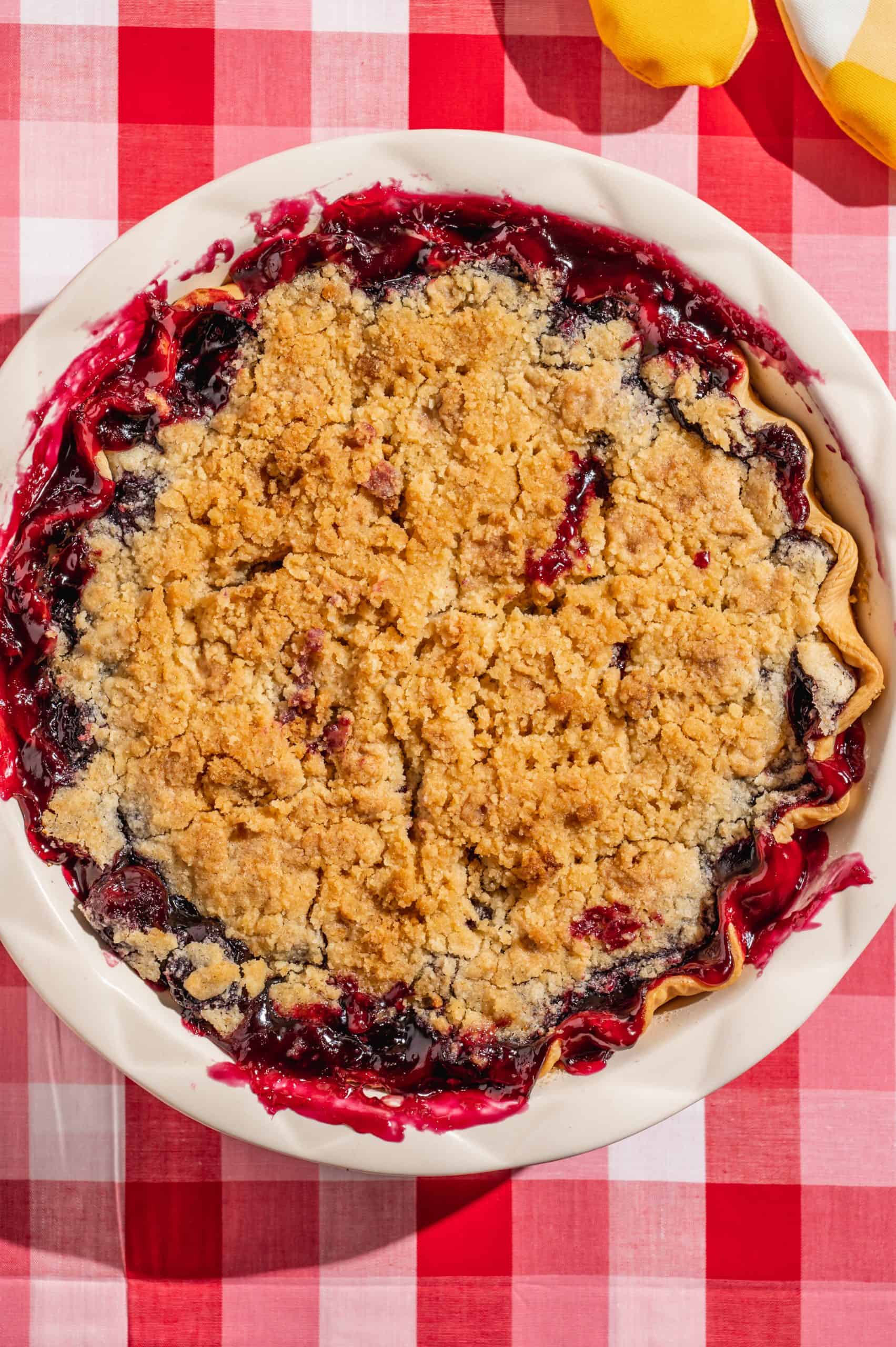 baked cherry pie with golden brown crumble topping and cherry filling oozing out the top