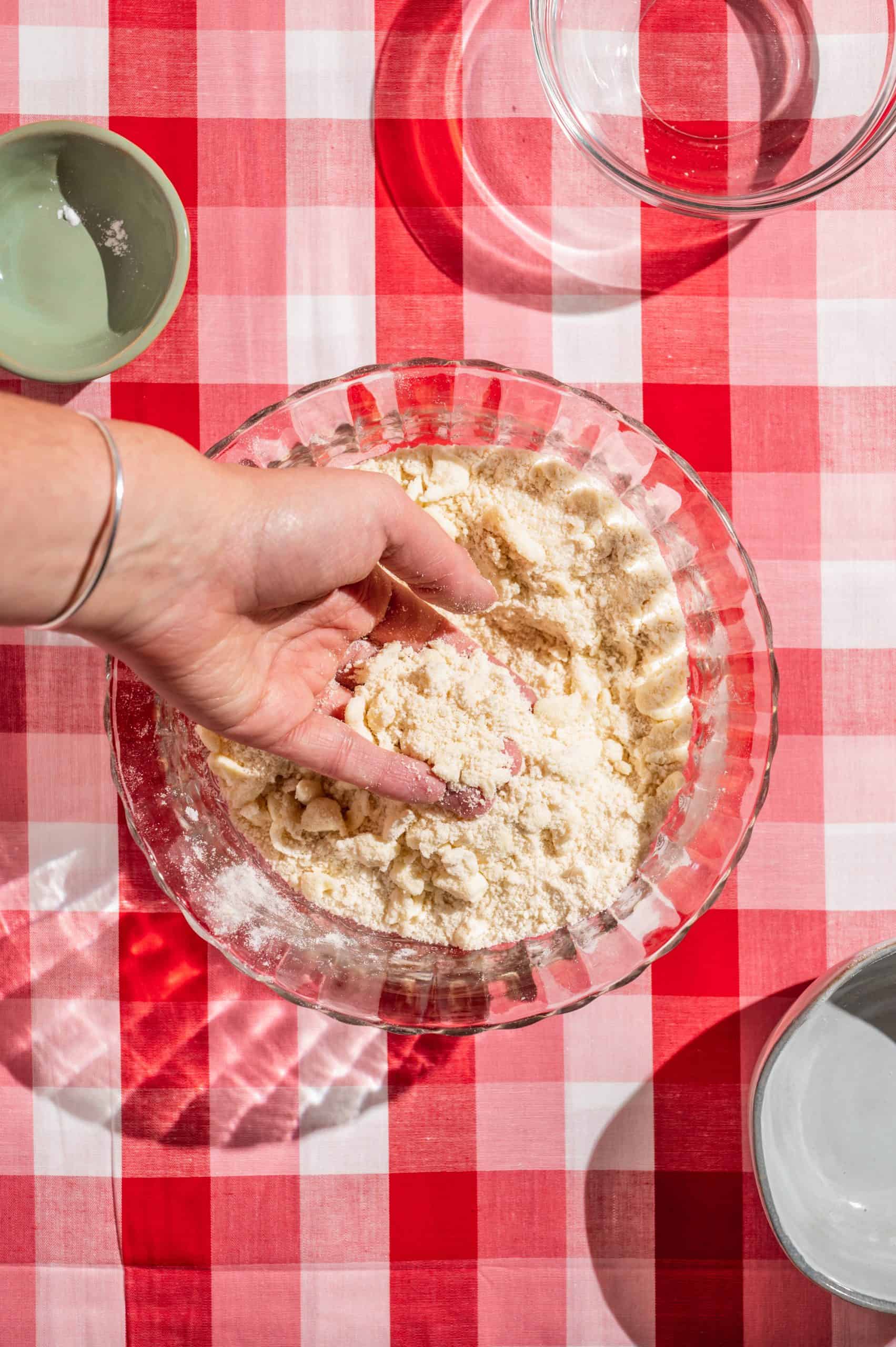 hand holding crumbly mixture of butter, flour, and sugar for crumble pie topping