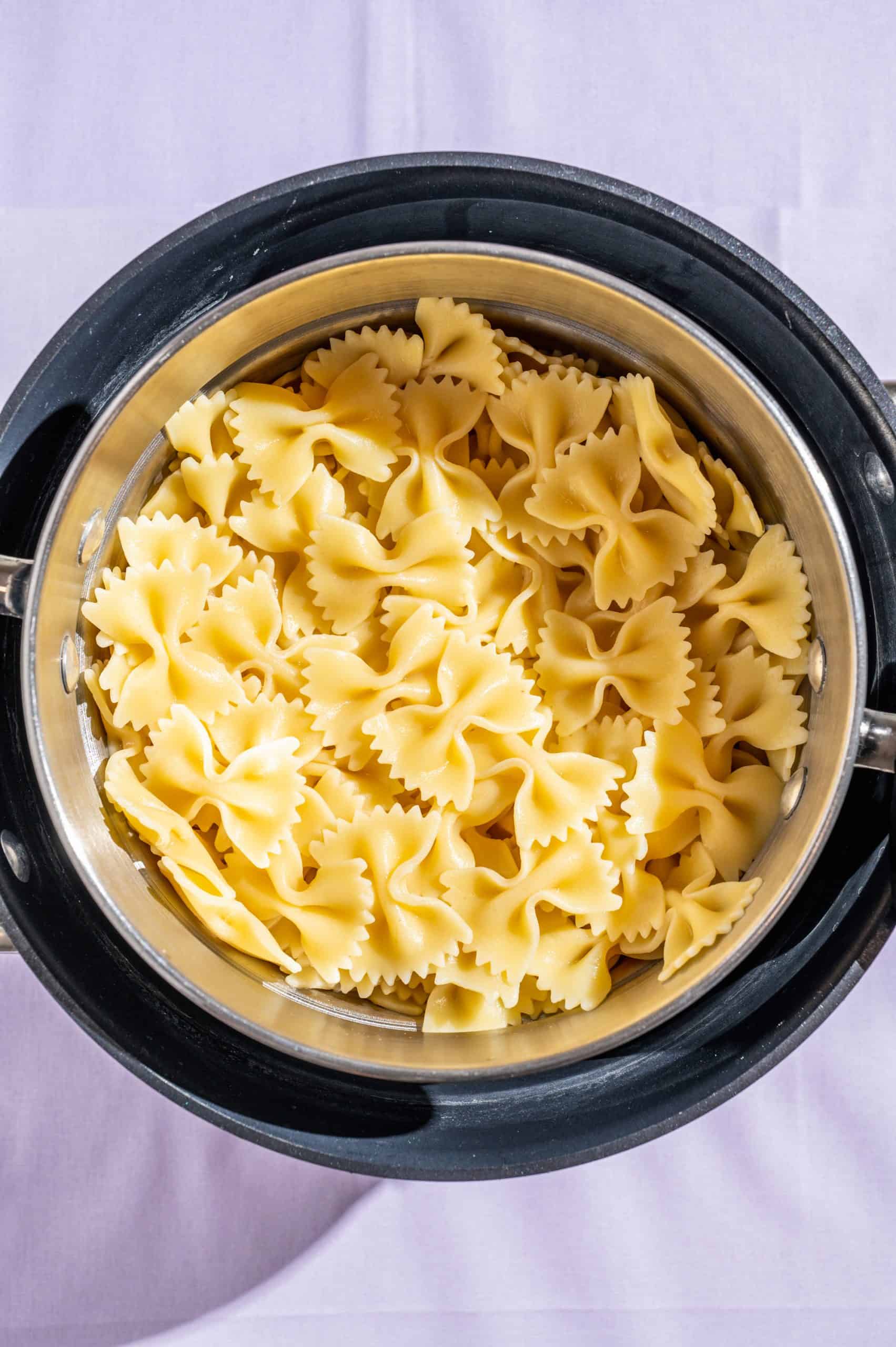 Farfalle bowtie pasta in a colander after cooking, draining, and rinsing.