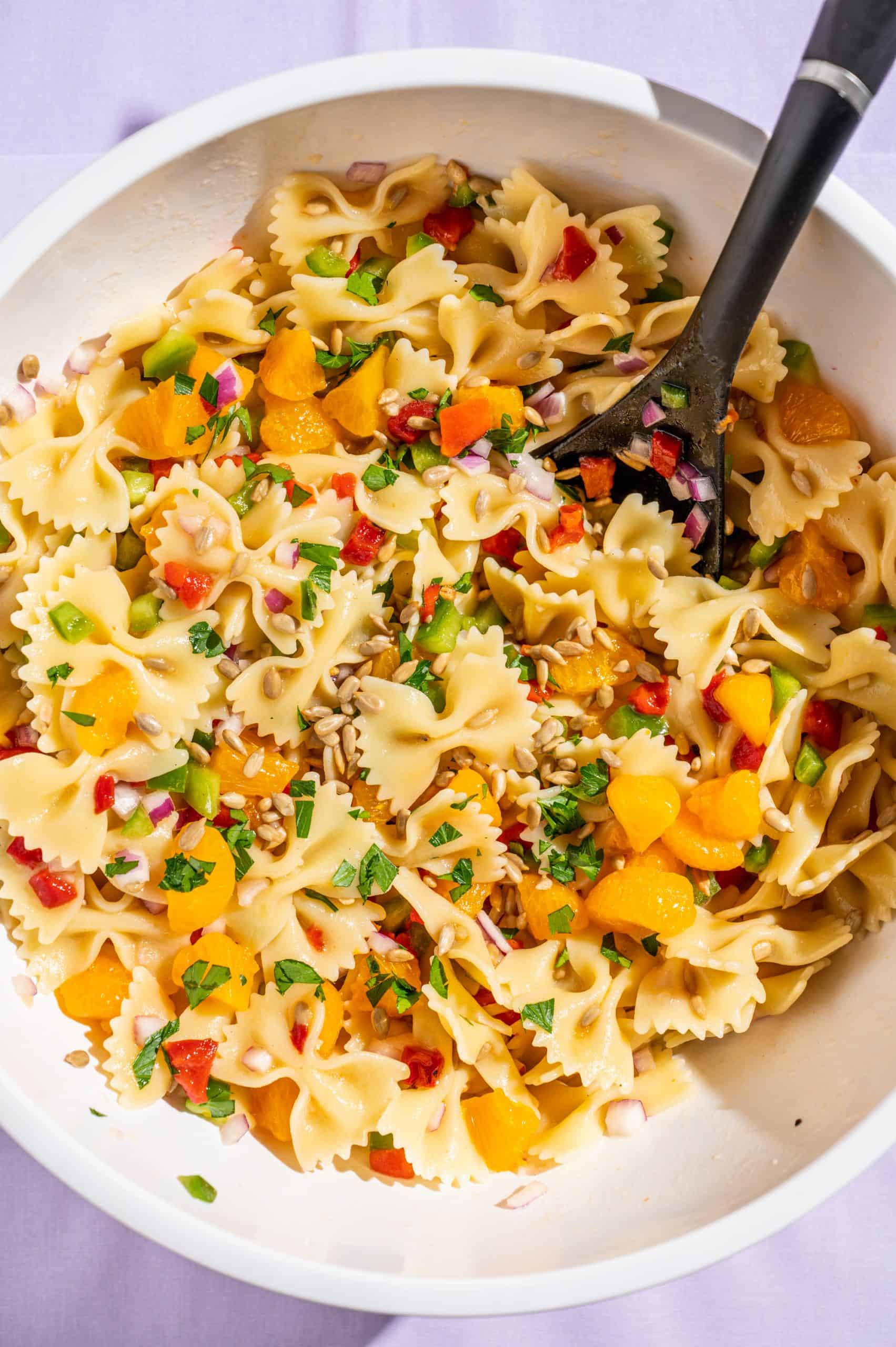 A large bowl of pasta salad after tossing pasta and other ingredients with honey vinaigrette.