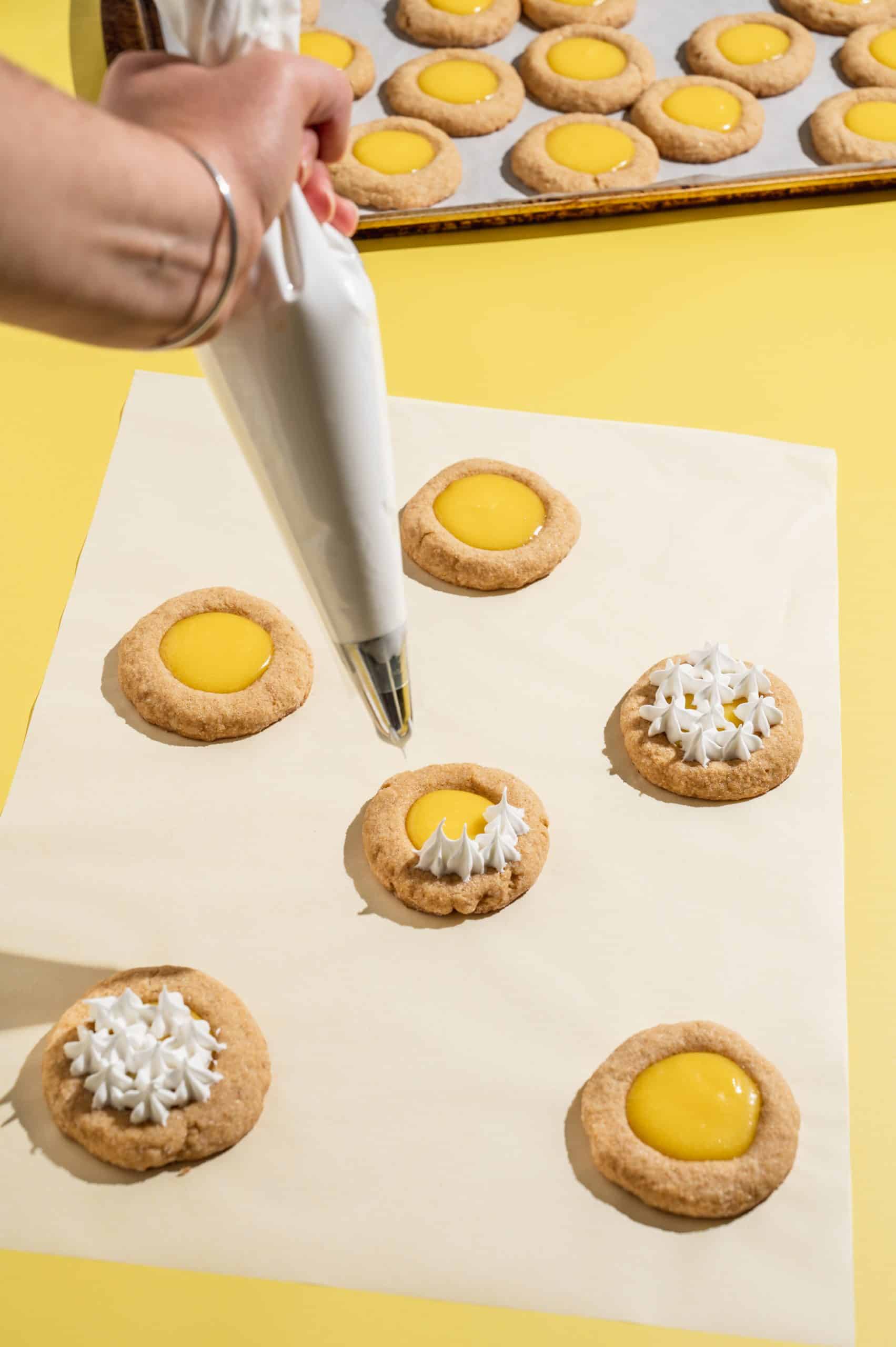 piping Swiss meringue on top of lemon curd thumbprint cookies