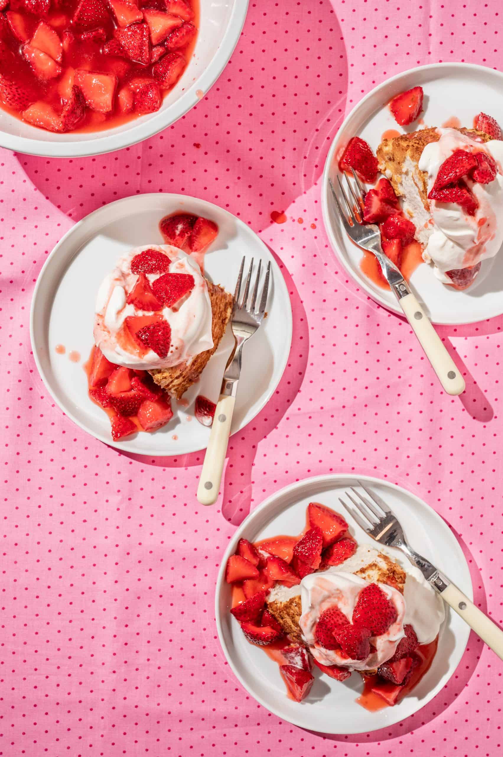 three plates with strawberry shortcake angel cake and extra strawberry topping on the side