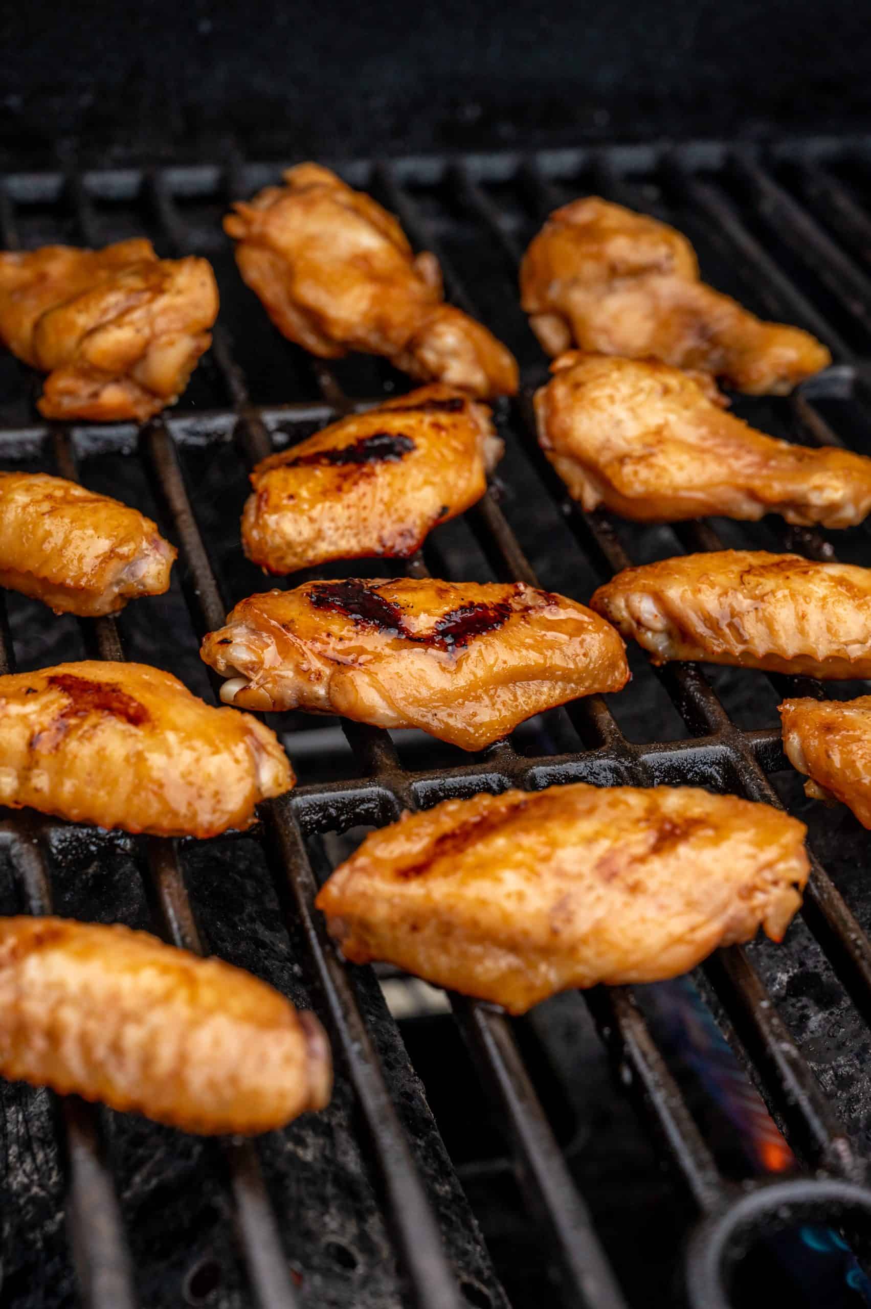 12 chicken wings getting crispy skin on a hot grill