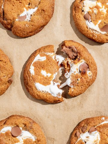 close up of warm chocolate chip cookie with marshmallow fluff center broken in half on a tray